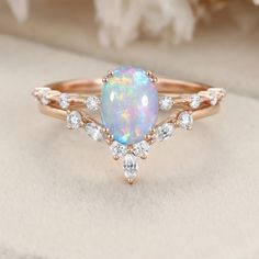 a white opal and diamond ring with rose petals in the background