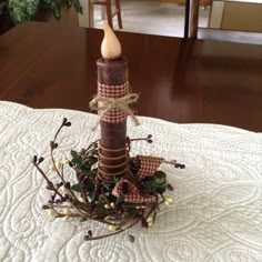 a candle is sitting on top of a table with some branches and berries around it