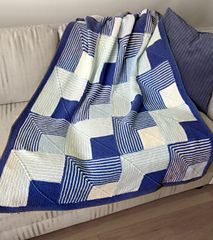 a blue and white quilt sitting on top of a couch