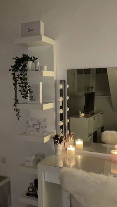 candles are lit in front of a mirror on the wall next to a white desk