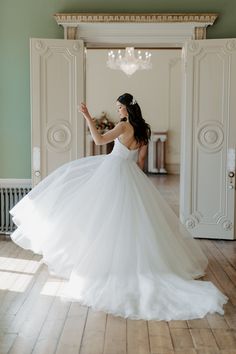 a woman in a white wedding dress is standing on the floor with her arms outstretched