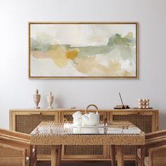 a painting hanging on the wall above a dining room table with chairs and a basket