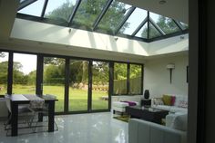 a living room filled with white furniture and lots of glass doors leading to an open field