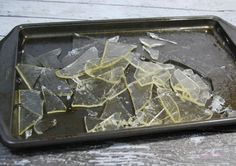 broken pieces of glass sitting on top of a metal tray next to a wooden table