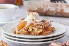 a plate topped with an apple cobbler next to a cup of coffee and cinnamon sticks