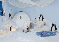 penguins are standing in an igloose decorated with lights and snowflakes