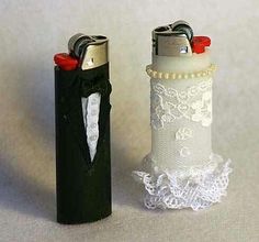 two lighters are next to each other on a white tableclothed surface, one is decorated with lace and the other has a red nosepiece