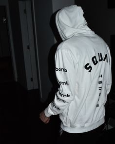 a man wearing a white hoodie with the word squad on it and black lettering