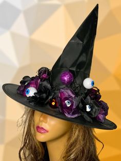 a black hat with purple flowers and googly eyes is on top of a mannequin head