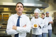 three chefs are standing in the kitchen with their arms crossed and one is holding a piece of food