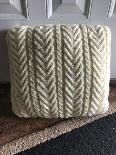 a white knitted pillow sitting on top of a rug