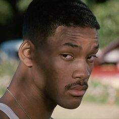 a close up of a person with a moustache on his face and wearing a necklace