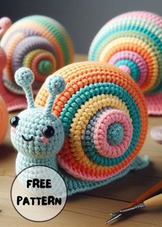 a crocheted snail is sitting on the table next to other crocheted snails