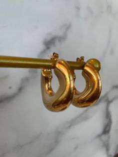 ✨Meet Leilani—where classic elegance meets modern allure. These gold-plated beauties are crafted with a chic, open-hoop design, radiating a lustrous shine that catches the light from every angle. ✨Their sleek, curved form is both bold and sophisticated, making them the perfect accessory for the woman who loves to command attention with understated luxury. ✨Ideal for both day and night, Leilani elevate any look with effortless grace. Whether paired with a power suit or a glamorous evening dress, they add a touch of timeless elegance and sensuality. ✨Let the Leilani Earrings be your go-to for a refined, yet daring, statement. Chic Tarnish-resistant Wedding Jewelry, Luxury Metal Jewelry With Gold-tone Hardware, Classic Gold Tarnish Resistant Hoop Earrings, Classic Gold Tarnish-resistant Hoop Earrings, Luxury Gold-tone Brass Jewelry, Luxury Brass Jewelry With Gold-tone Hardware, Everyday Elegance Tarnish-resistant Hoop Jewelry, Elegant Polished Yellow Gold Hoop Earrings, Elegant Yellow Gold Polished Hoop Earrings