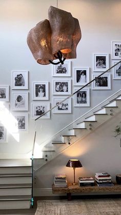 a staircase with pictures on the wall and a lamp hanging from it's side