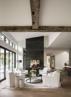 a living room with white chairs and a fireplace