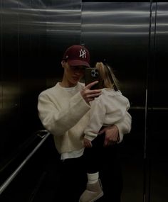 a woman taking a selfie with her cell phone in the elevator while wearing a new york yankees hat