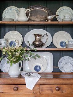 an old china cabinet is filled with dishes and cups, including one that has flowers in the vase