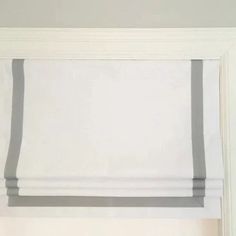 a white window with grey stripes on the top and bottom blinds in front of it