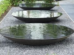 three metal bowls sitting on top of gravel