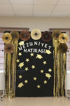 a black backdrop with gold tassels and paper flowers on it that says mezunivet hatirasi