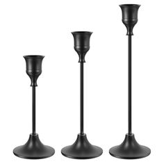 three black candlesticks sitting next to each other