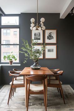 a dining room table and chairs with pictures on the wall behind it in front of a window