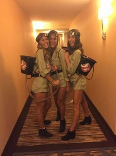 three girls in uniform are standing on the hallway way with their backpacks over their backs