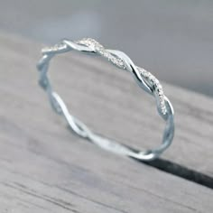 a white gold wedding band with twisted leaves on the side, sitting on a wooden surface