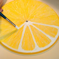 someone using a brush to paint the inside of an orange slice with yellow and white stripes