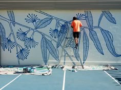 a man is painting a mural on the side of a building in an orange shirt