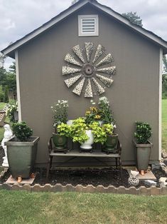 a garden shed with potted plants and a windmill decoration on the front door wall