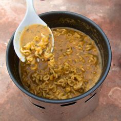 a ladle full of macaroni and cheese is being held by a spoon