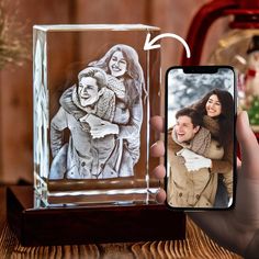 a person taking a photo with their cell phone next to a glass block that has an image of two people on it