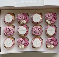 twelve cupcakes with pink frosting in a box