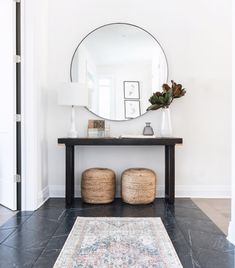 a large round mirror on the wall above a black table