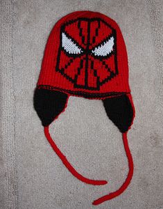 a red and black knitted hat with a spiderman face on it's side