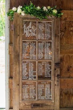 a wooden sign with white flowers and greenery on it