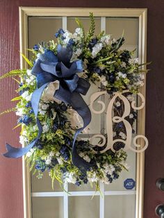 a wreath with the letter b on it hanging in front of a door decorated with blue and white flowers