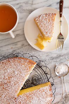 a piece of cake on a plate next to a cup of tea and a fork