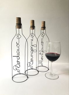 three wine bottles and a glass sitting next to each other in front of a white background