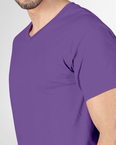 a man wearing a purple t - shirt and glasses is looking at the camera with his hands in his pockets