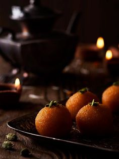 small oranges on a plate with candles in the background