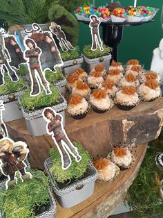 cupcakes are arranged on top of a wooden table with pictures of people and plants