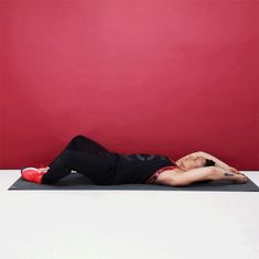 a man laying on top of a yoga mat in front of a red wall