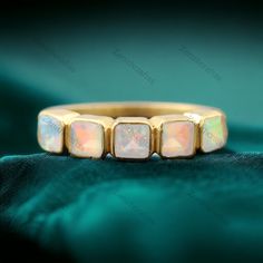 a gold ring with three opal stones in it on a green velvet background, close up