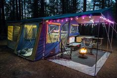 a tent set up in the woods with lights on