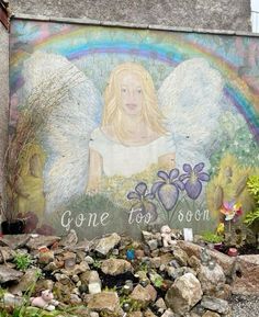 a painting on the side of a building with an angel and flowers painted on it