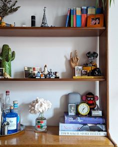 three wooden shelves with books, vases and other items on top of each shelf