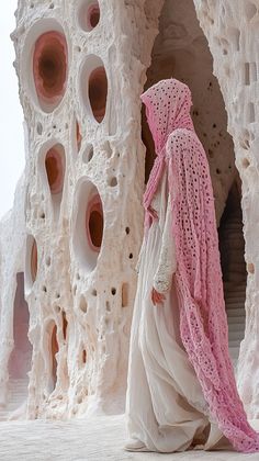 a woman in a white dress and pink shawl is walking through an art installation